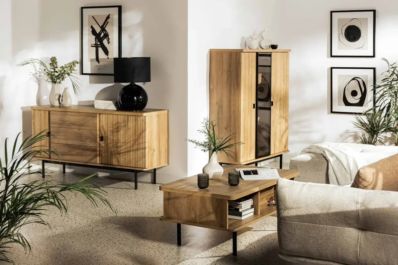 Przytulny **styl hygge wnętrza** z drewnianymi meblami, czarną lampą i roślinami.