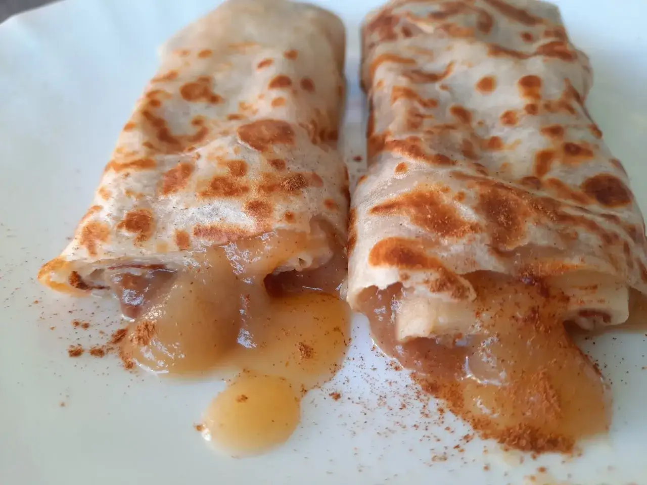 Zwei goldbraune Pfannkuchen, gef&uuml;llt mit Apfelmus und Zimt, ein k&ouml;stliches Pfannkuchen Rezept.