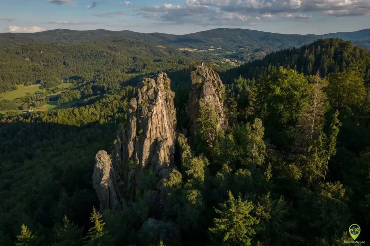 Skaliste szczyty, jak sokolik duży, górują nad lasem. Na jednym z nich platforma widokowa z turystą.