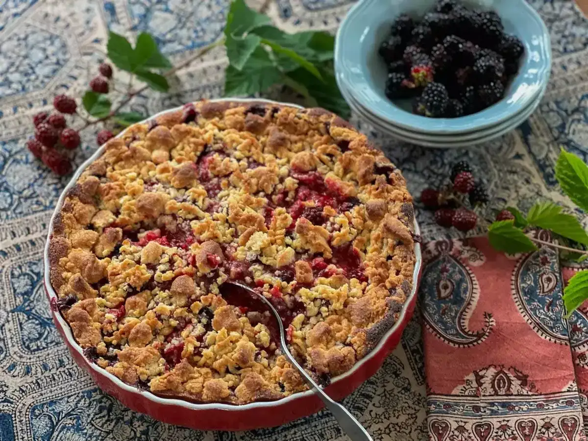 Un d&eacute;licieux crumble fruits rouges, dor&eacute; et croustillant, pr&ecirc;t &agrave; &ecirc;tre d&eacute;gust&eacute;. Des m&ucirc;res fra&icirc;ches dans un bol &agrave; c&ocirc;t&eacute;.