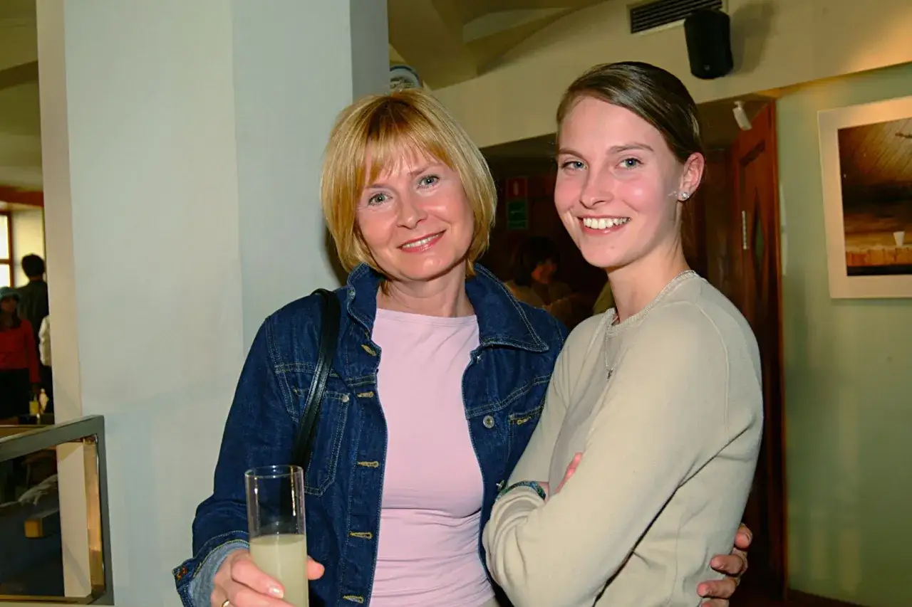 Barbara Bursztynowicz z córką uśmiechają się do zdjęcia. Kobieta po lewej trzyma szklankę z napojem.