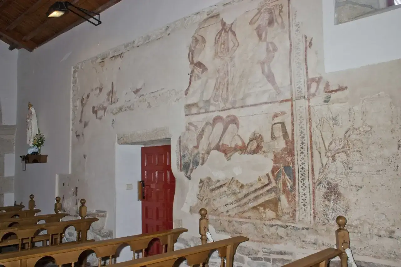 Antiguos frescos en una iglesia, con una imagen de la Virxe da Mari&ntilde;a y bancos de madera.
