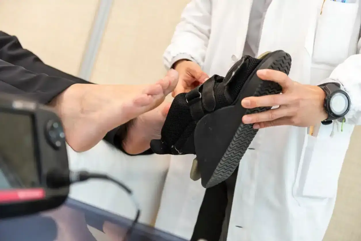 Arzt zeigt orthop&auml;dischen Schuh zur Linderung von Hallux-Schmerzen. Hausmittel k&ouml;nnen hierbei unterst&uuml;tzen.
