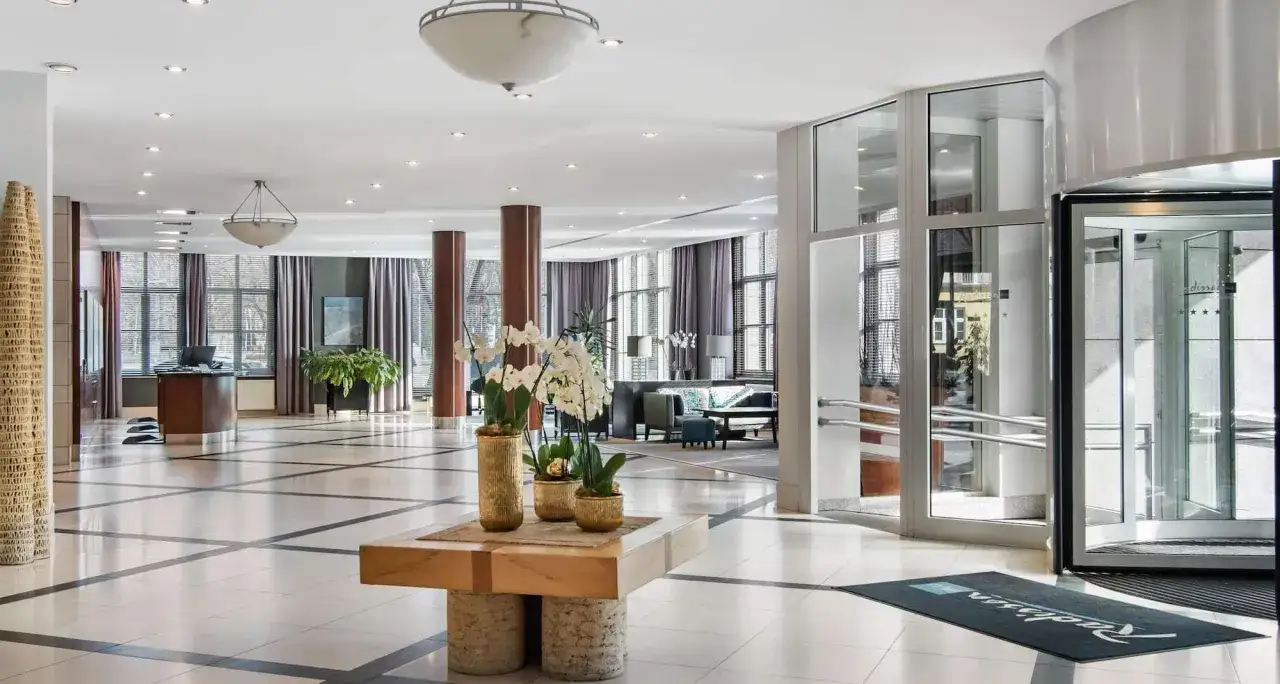 Eleganckie wnętrze hotelu Radisson Blu Wrocław z recepcją, wygodnymi sofami i ozdobnymi kwiatami.