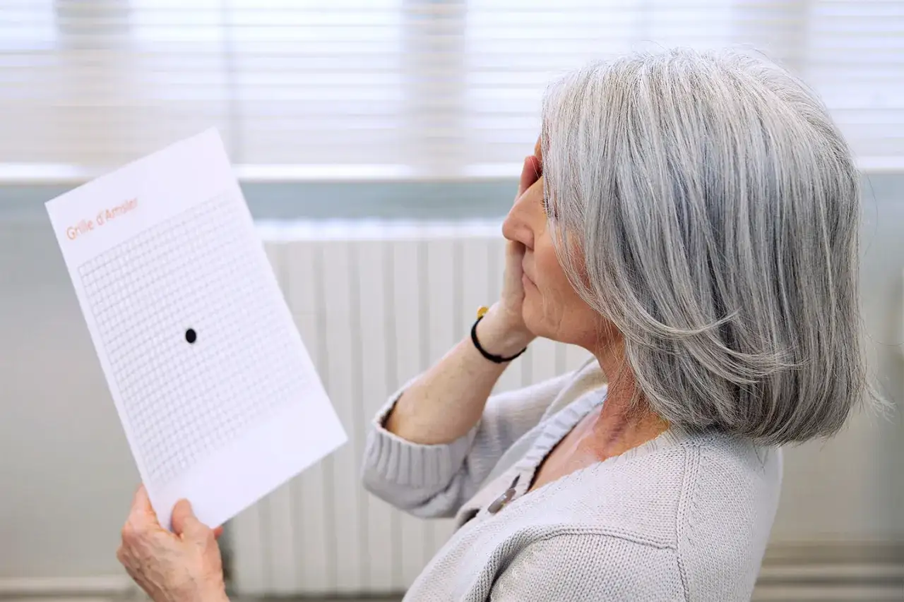 Kobieta wykonuje test Amslera, aby sprawdzić, czy nie ma zwyrodnienia plamki żółtej. Widoczna jest siatka z kropką pośrodku.