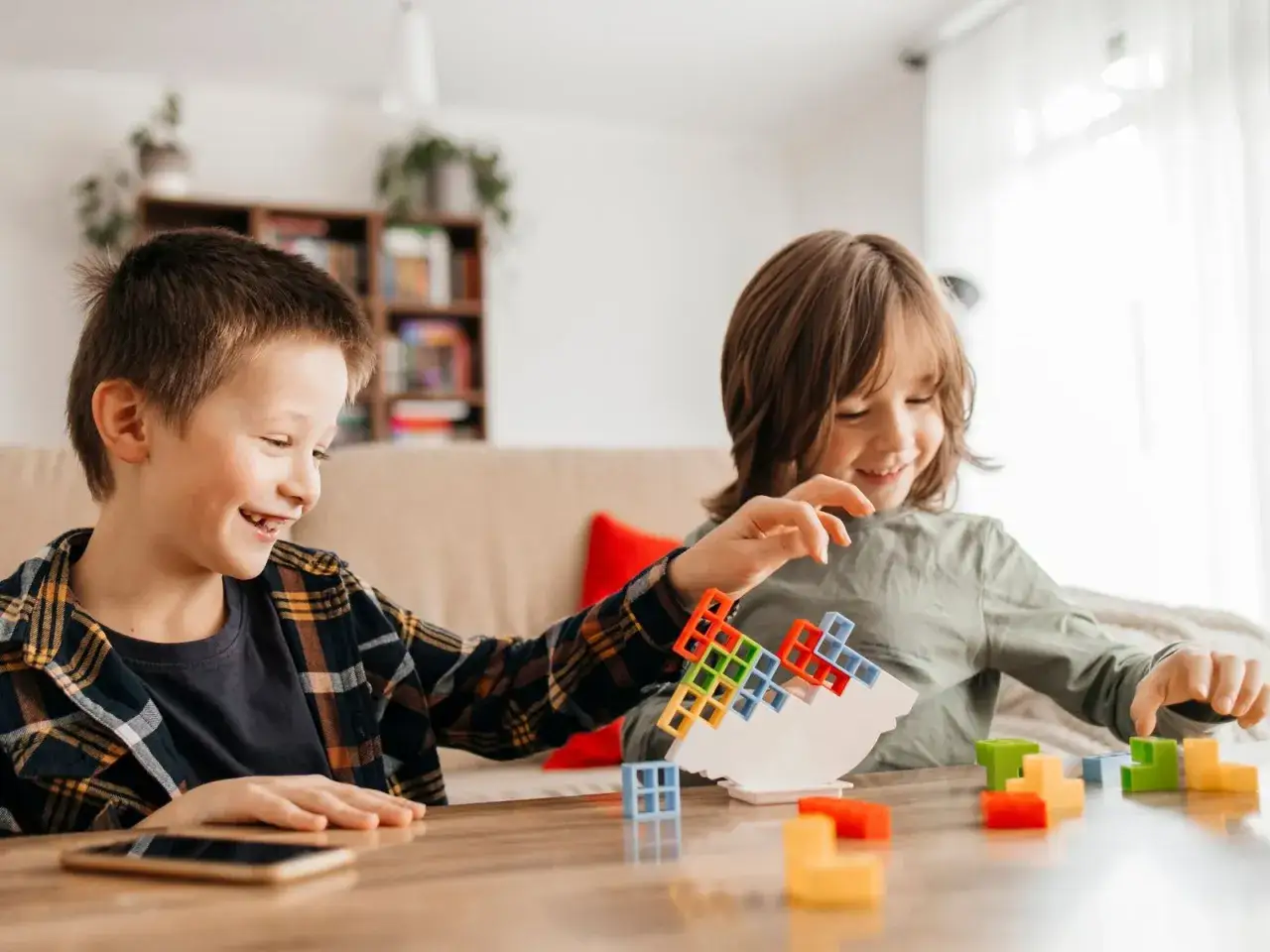 Zwei lachende Jungen spielen mit bunten Bausteinen. Ein spannendes Spiel, das an lustige Klassenspiele Grundschule erinnert.