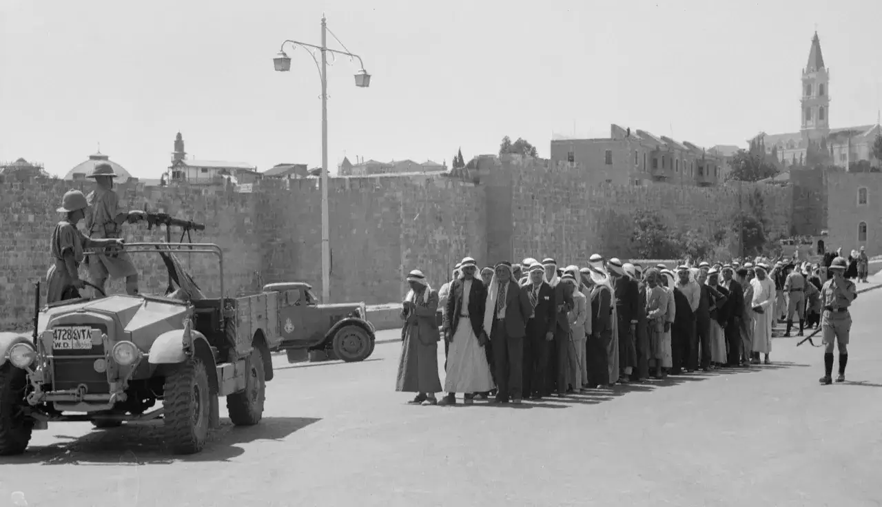 Soldater med vapen vid en bil, en rad m&auml;n i traditionella kl&auml;der. Bilden kan illustrera vad zionist betyder i en historisk kontext.