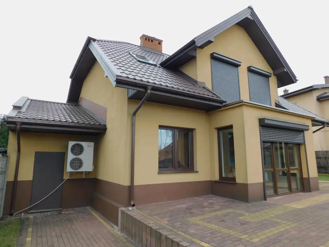 Nowy dom z roletami, idealny na licytacja nieruchomości kpc. Jasnoż&oacute;łty tynk, brązowy dach i okna.