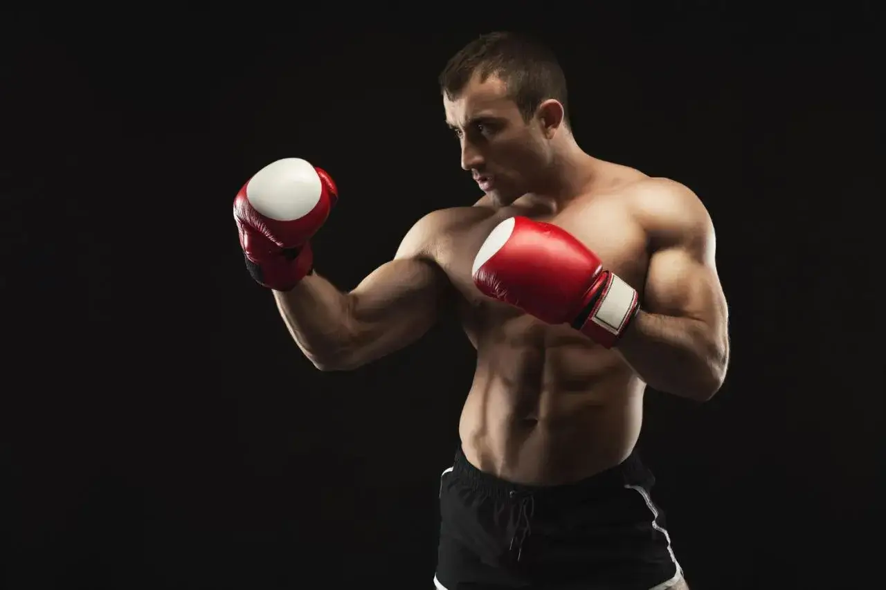 A muscular boxer in a fighting stance, wearing red gloves, embodies hitman style boxing with intense focus.