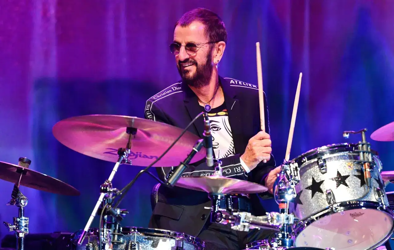 Ringo Starr, perkusista The Beatles, gra na perkusji w błyszczącej kurtce z napisem 