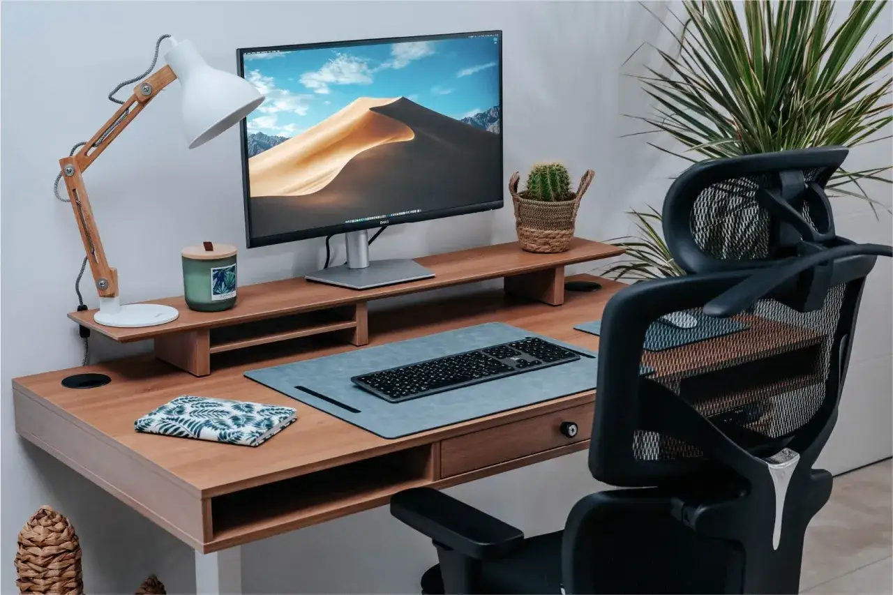 Bureau moderne avec &eacute;cran, clavier, lampe et plante. L'ergonomie du travail sur &eacute;cran est optimis&eacute;e pour le confort.