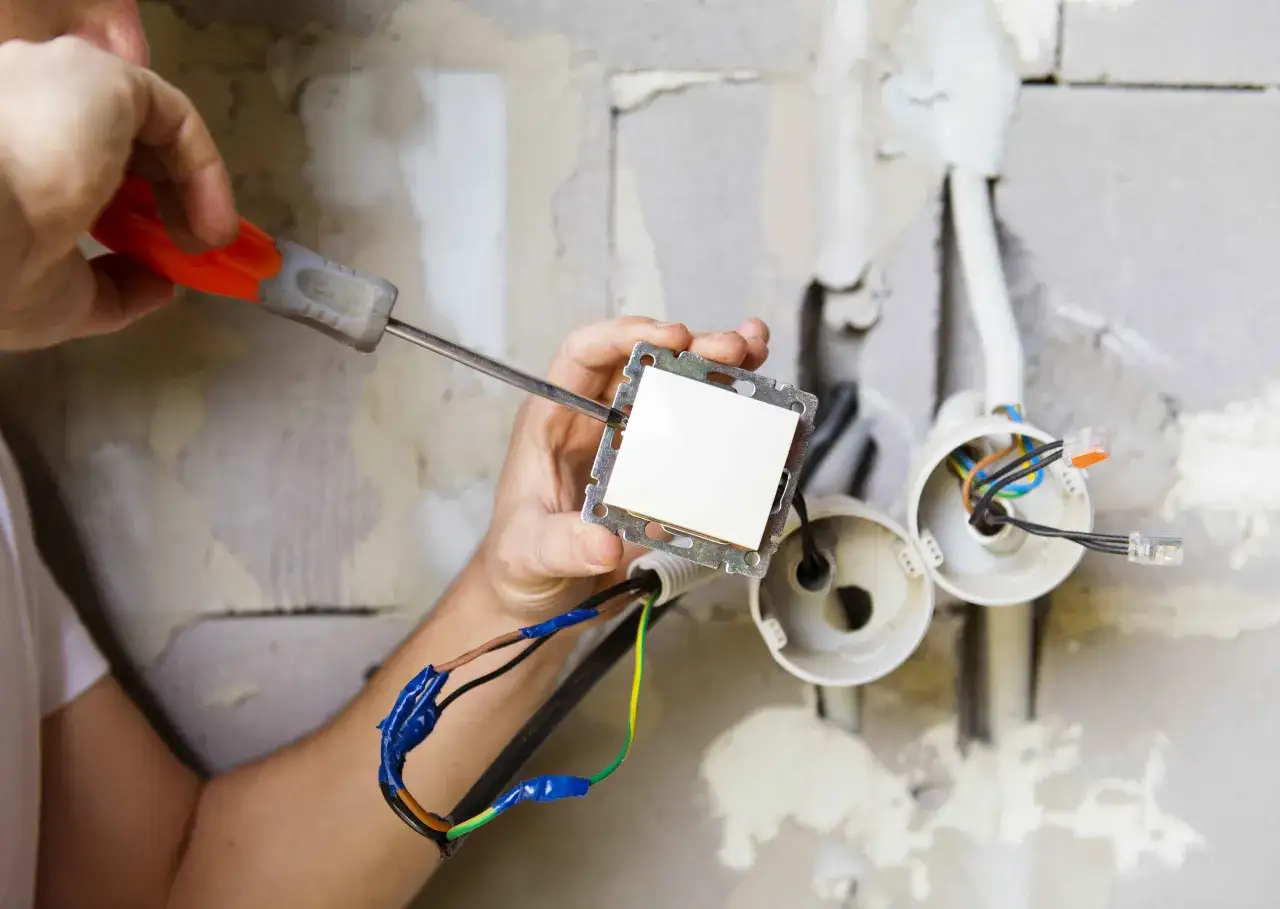 Instalator montuje gniazdko i włącznik w jednym, podłączając przewody.