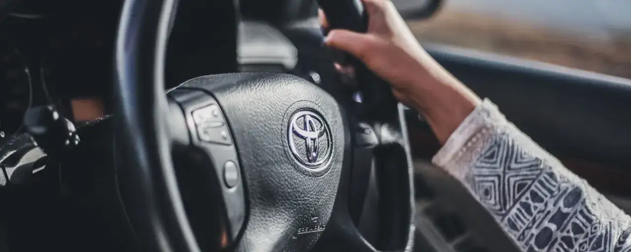 Mano sujetando el volante de un Toyota. De repente, la dirección asistida dura, causando sorpresa.