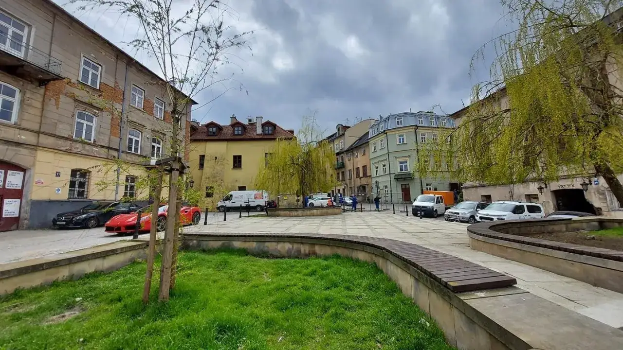 Plac rybny Lublin z kolorowymi kamienicami, zielenią i zaparkowanymi samochodami.