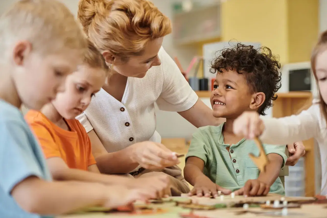 Lehrerin hilft Kindern bei einer ko konstruktion kita. Sie bauen etwas Kreatives zusammen.