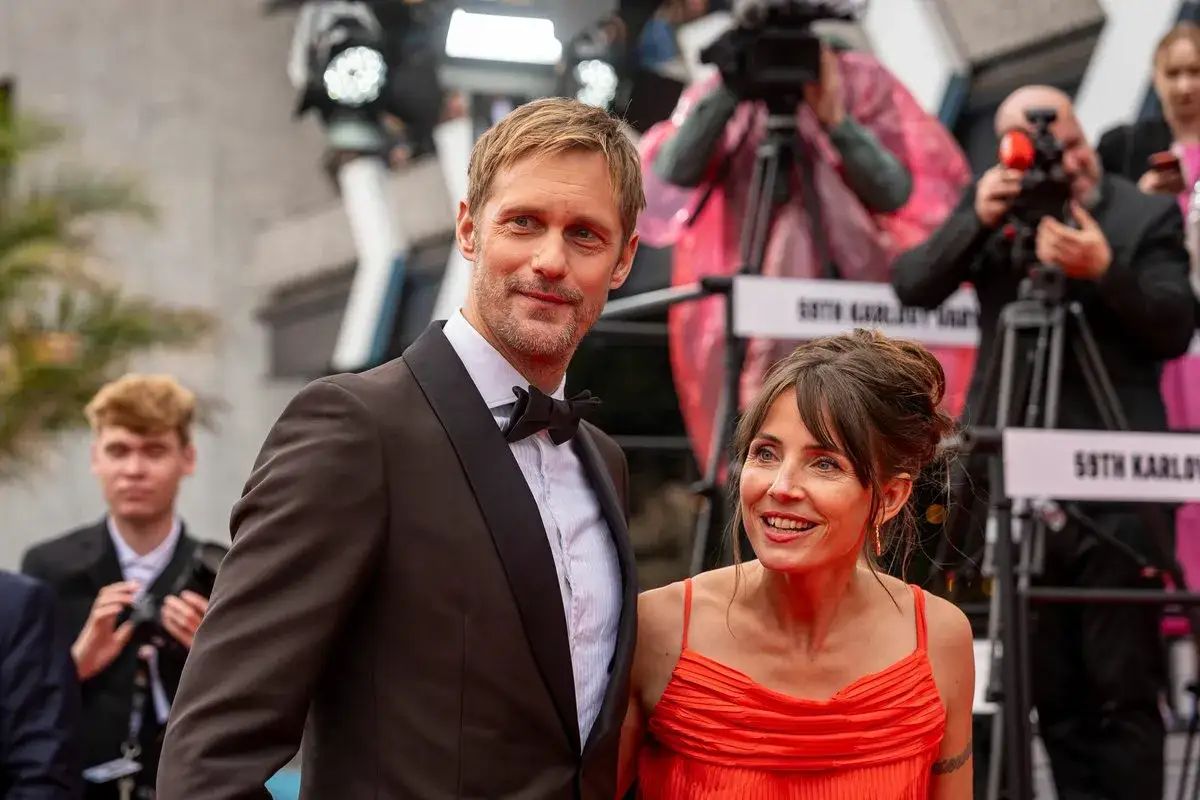 Alexander Skarsgård och Tuva Novotny på röda mattan, omgivna av fotografer.