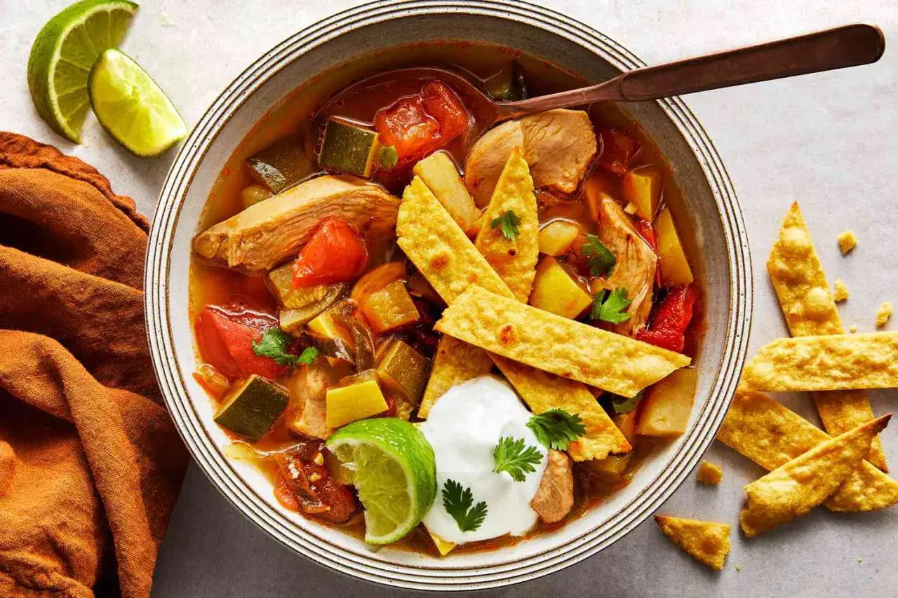 Pyszna, dietetyczna tortilla na kolację: sycąca zupa z kurczakiem, warzywami i chrupiącymi paskami tortilli, podana z limonką i śmietaną.