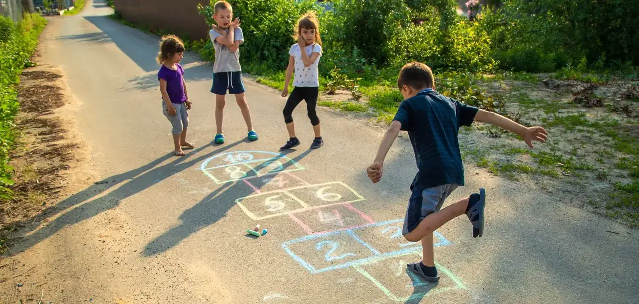 Niños jugando a la rayuela en la calle, un clásico de los juegos de patio.