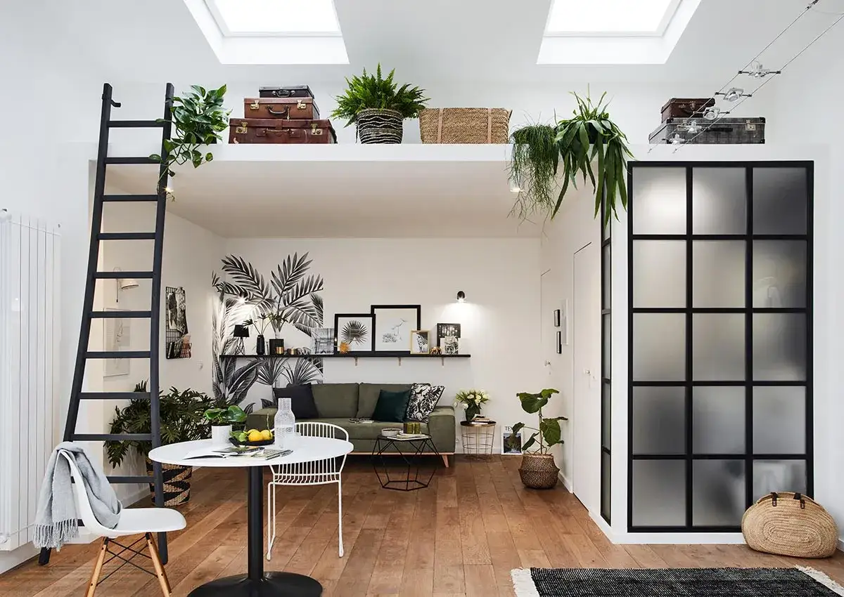Ce studio de 28 m2 optimisé offre un coin repas, un salon cosy et une mezzanine accessible par une échelle. Décoration végétale et style bohème.