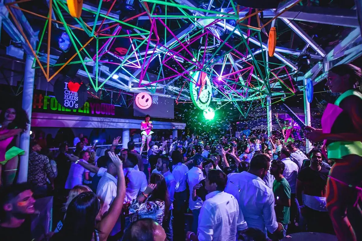 Festa in una discoteca in Emilia Romagna, con luci al neon, coriandoli e gente che balla. #ForeverYoung
