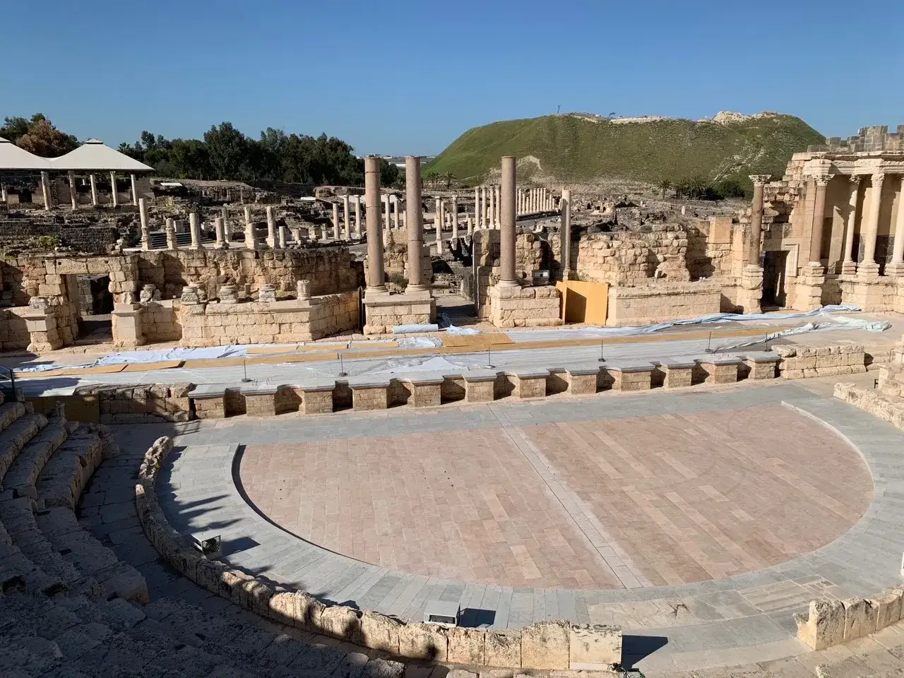 Ancient Roman theater ruins, perhaps where Ray Vander Laan once taught, with stone seating and a stage under a clear blue sky.