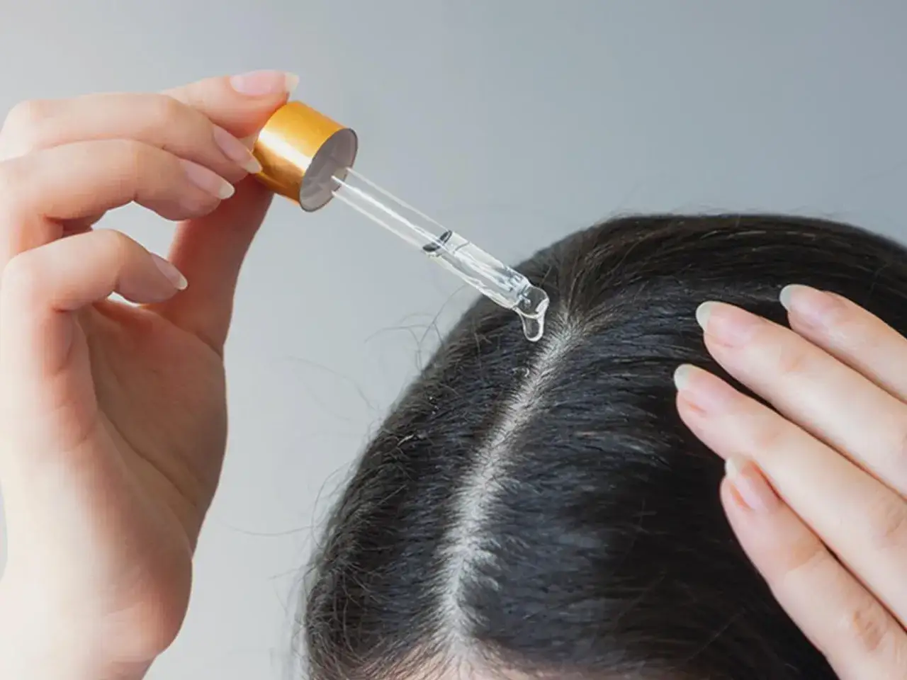 Eine Hand tr&auml;gt mit einer Pipette &Ouml;l auf die Kopfhaut auf, um juckende Kopfhaut Hausmittel anzuwenden.