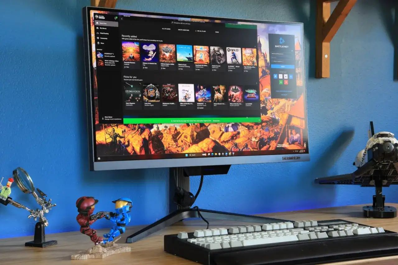 Jaki monitor do gier? Ekran wyświetla menu Xbox Game Pass z grami, obok klawiatura i figurki.