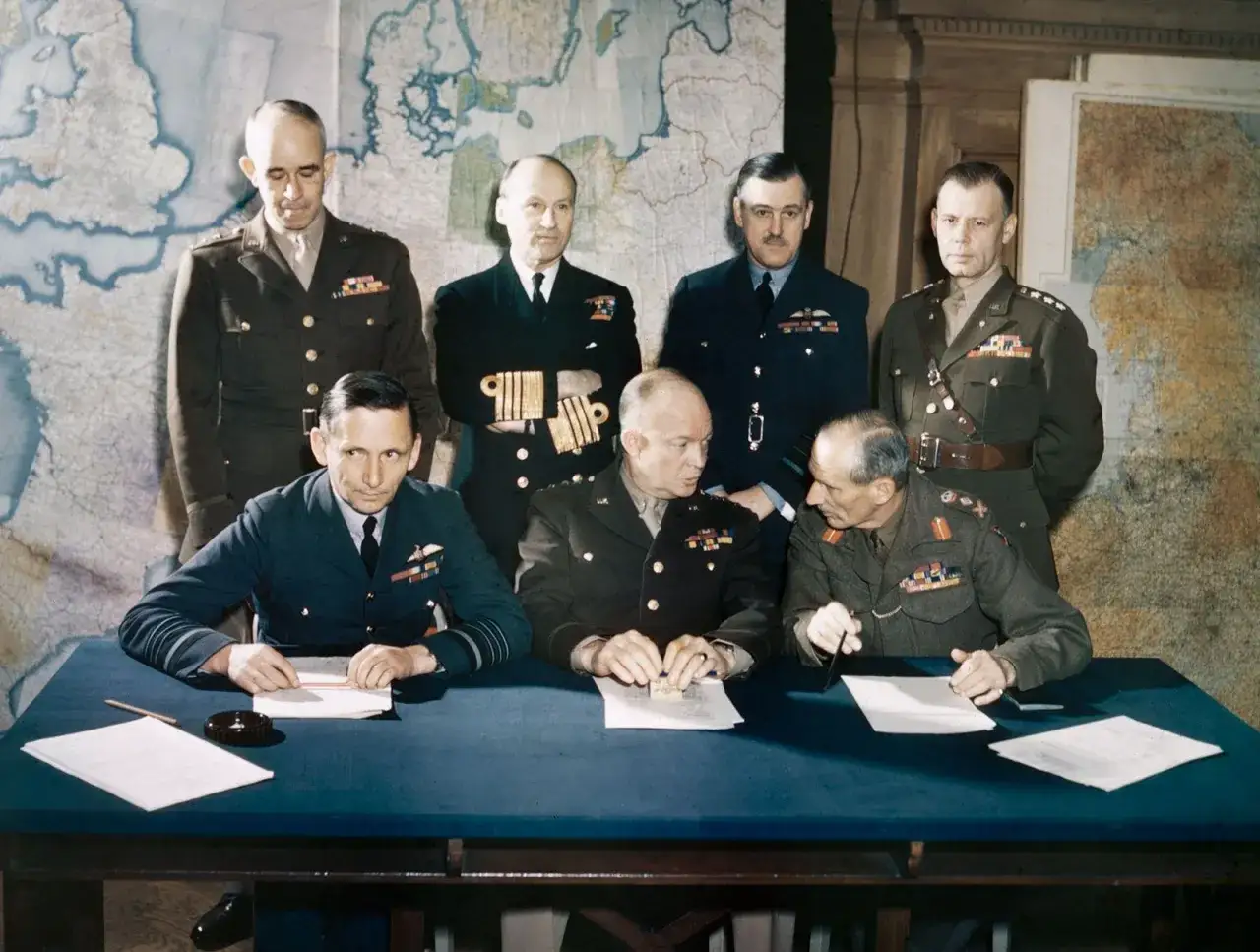 Sju militärer samlade vid ett bord, bakom dem en karta. En av dem skriver under ett dokument, en viktig dag d datum.