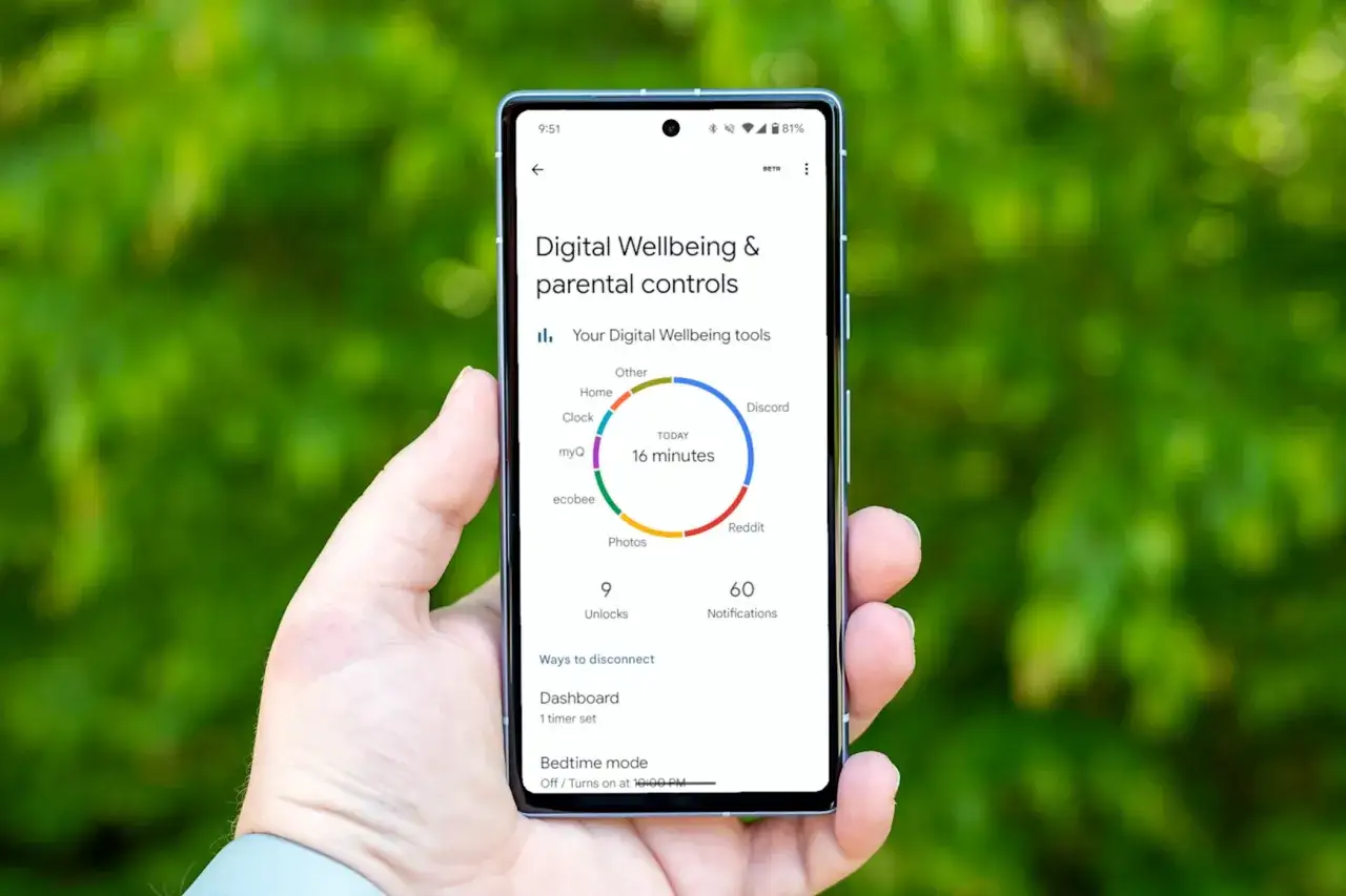 Dłoń trzyma smartfon z ekranem pokazującym narzędzia do zarządzania czasem przed ekranem. Widoczny wykres i statystyki użytkowania.