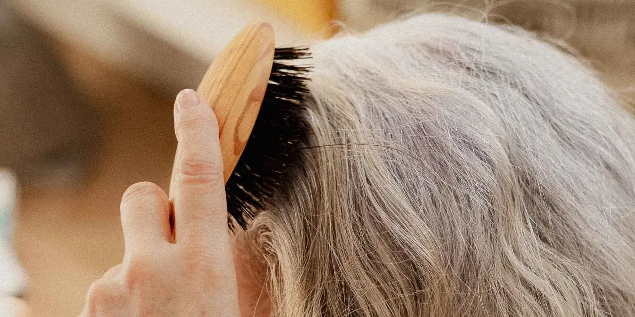 Une main brosse des cheveux gris, secs, une pr&eacute;occupation courante durant la m&eacute;nopause.