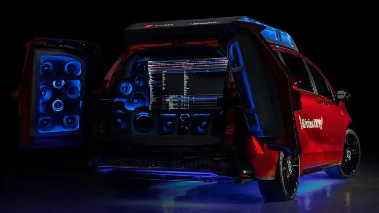 Un coche rojo con puertas traseras abiertas, mostrando un sistema de sonido con luces azules y una pantalla de DJ. ¡Esto es parkineo que es!