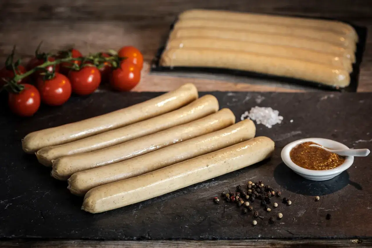 Frische Bratw&uuml;rste liegen bereit. Woher kommt die Bratwurst? Wahrscheinlich aus einer traditionellen Metzgerei, bereit f&uuml;r den Grill. Dazu Tomaten, Senf und Pfeffer.