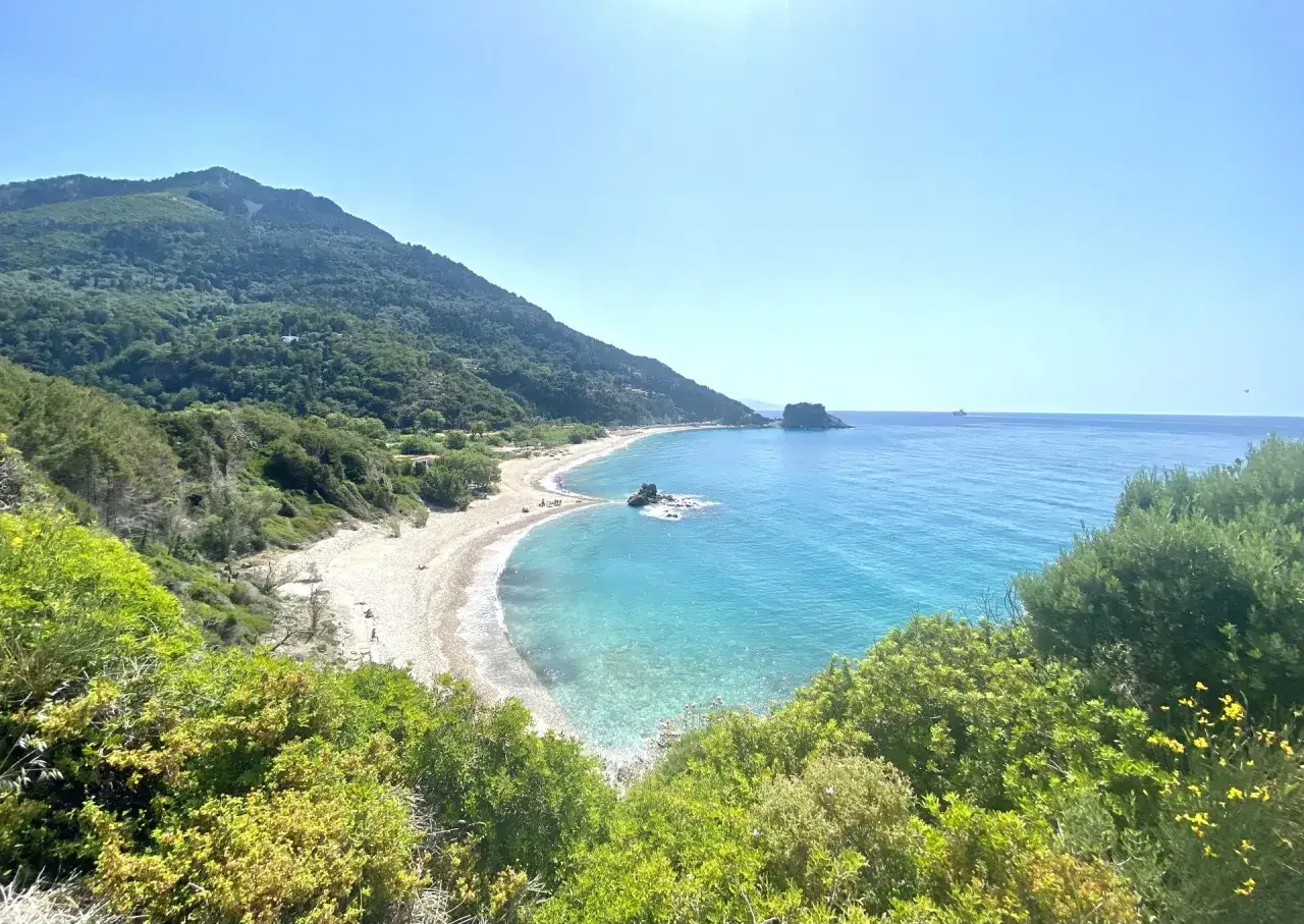 Malownicza zatoka z piaszczystą plażą i turkusową wodą, otoczona zielonymi wzgórzami. Idealne miejsce na wypoczynek, jak samos miasto.