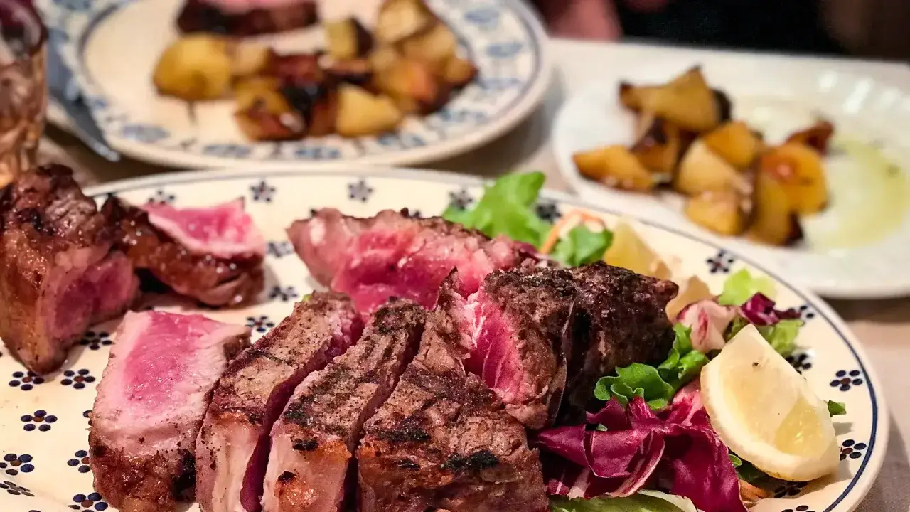 En saftig bistecca alla fiorentina, perfekt grillad med en rosa k&auml;rna, serveras med krispig sallad och citronklyfta.