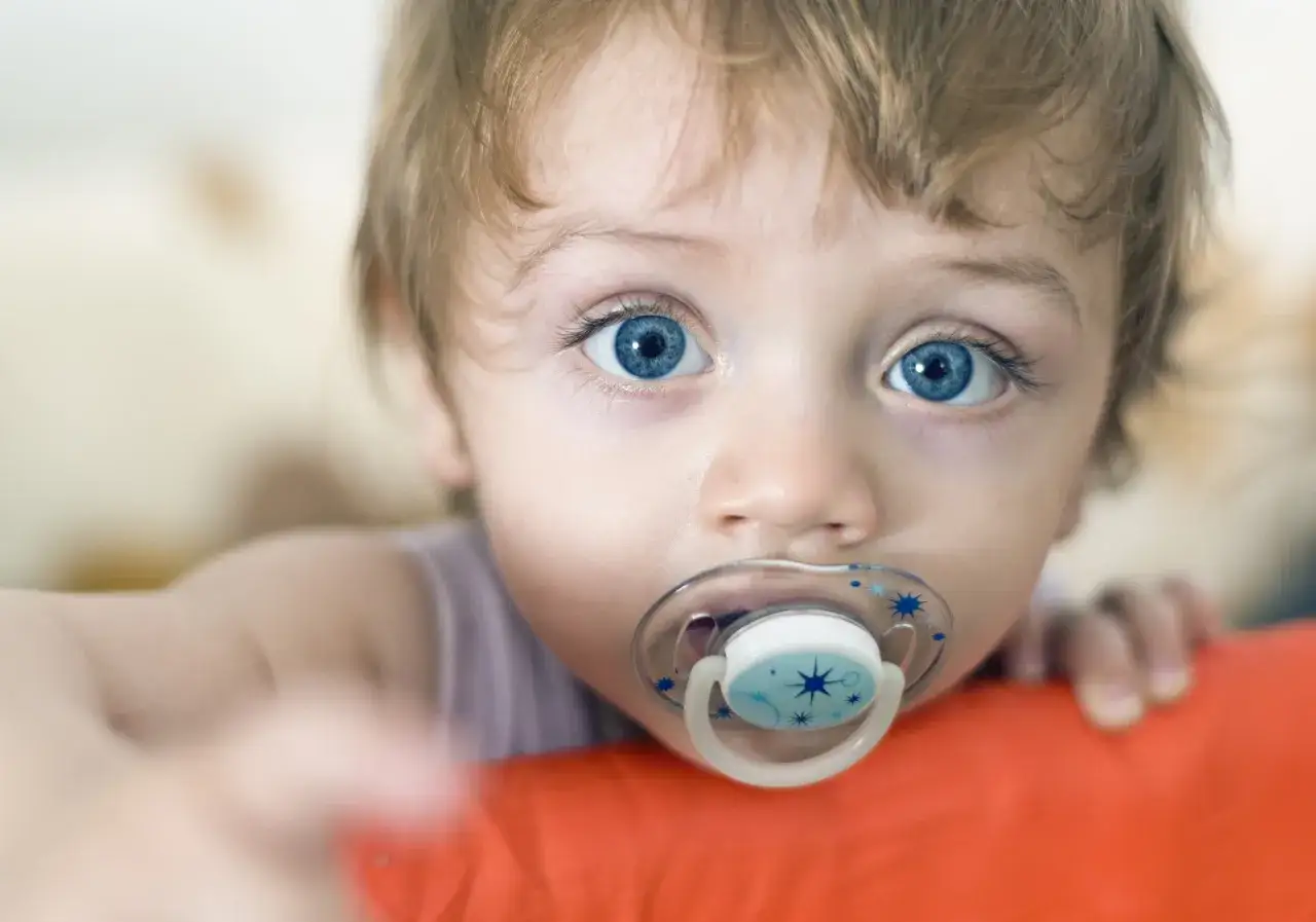 Bebé con chupete azul. Aprende cómo esterilizar chupetes para mantenerlo limpio y seguro.