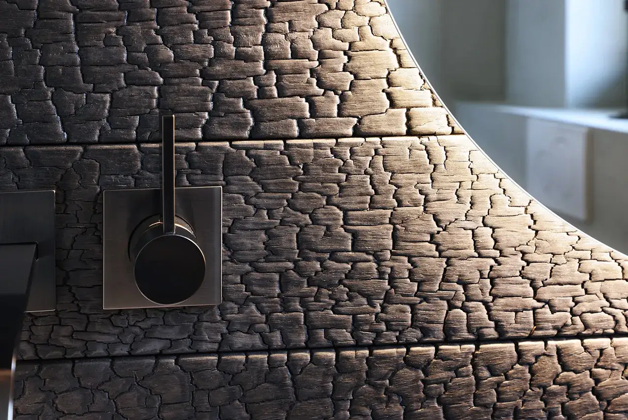 Ein moderner Wasserhahn auf einer Wandverkleidung im Shou Sugi Ban Stil. Die verkohlte Holzoberfl&auml;che zeigt eine faszinierende Textur.