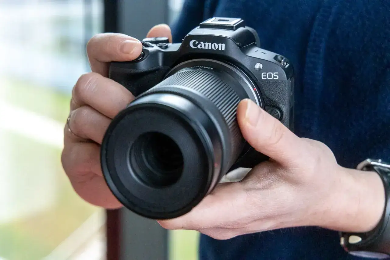 Mains tenant un appareil photo Canon EOS R50, pr&ecirc;t pour un test.