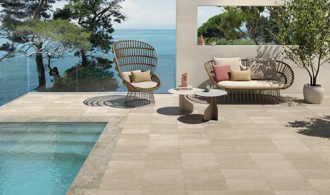 Terrazza con piscina e arredi da esterno, pavimentata con eleganti mattonelle per esterni color sabbia.