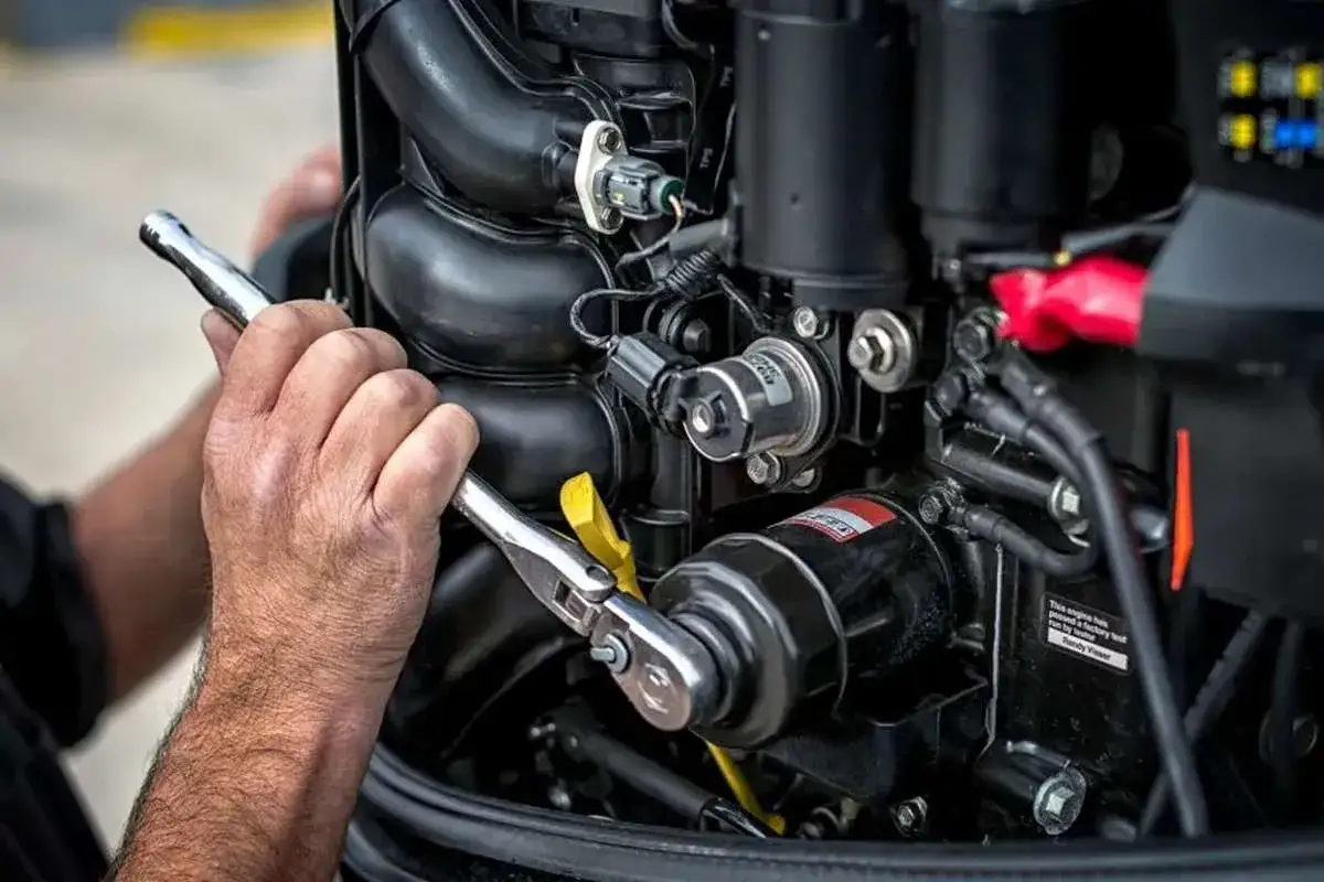 Main d'un m&eacute;canicien ajustant le moteur d'un voilier moteur avec une cl&eacute;.