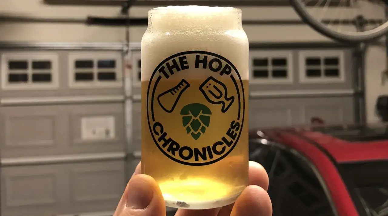 Un verre de bière blonde avec une mousse abondante, orné du logo