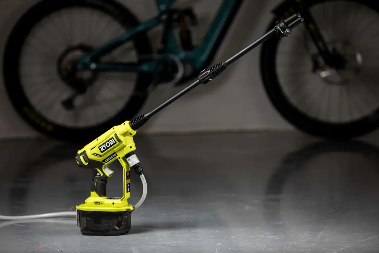 En gr&ouml;n och svart h&ouml;gtryckstv&auml;tt fr&aring;n Ryobi, liknande en K&auml;rcher OC3, st&aring;r redo att reng&ouml;ra en smutsig cykel.