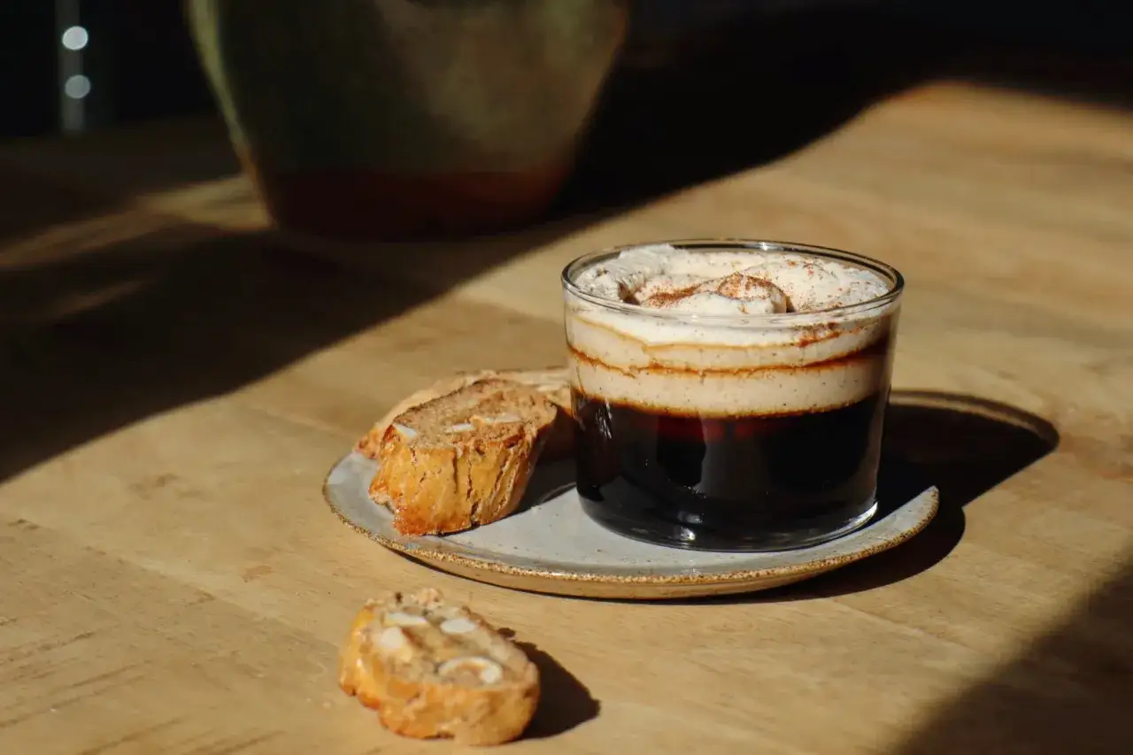 En lyxig kaffedrink med grädde och kanel, serverad med mandelkakor. Perfekt för att baka snabbt fika.