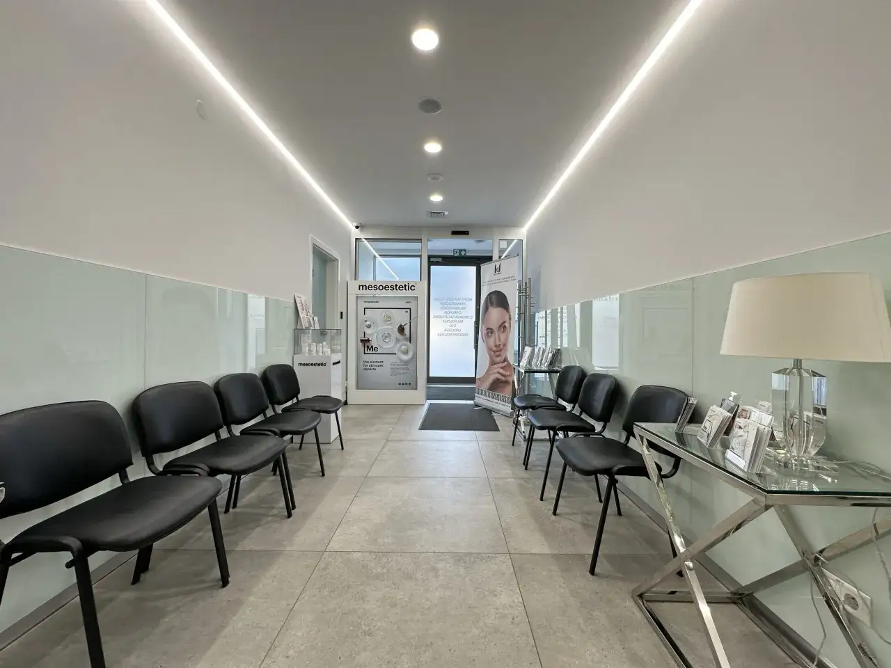 Nowoczesna poczekalnia kliniki dermatologii estetycznej z czarnymi fotelami i plakatem.