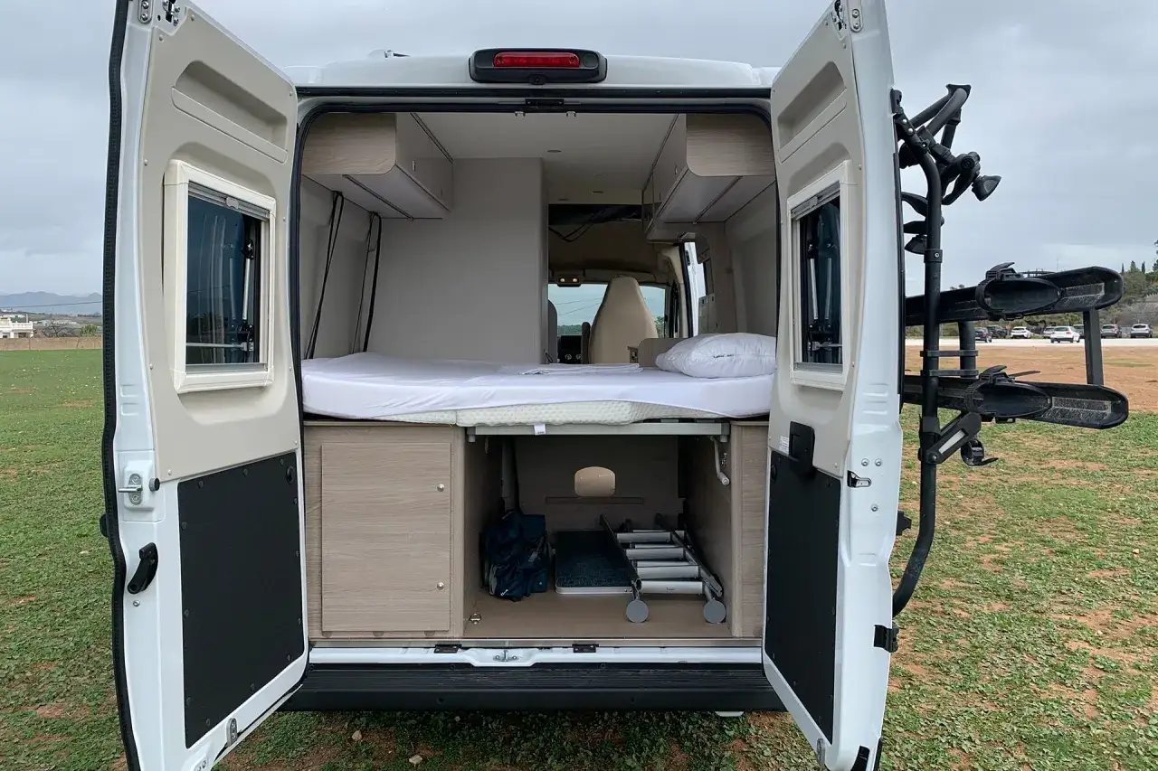 Am&eacute;nagement int&eacute;rieur d'un camping-car pr&ecirc;t pour le camping chez l'habitant en Espagne. Lit, rangements et porte-v&eacute;los visible.