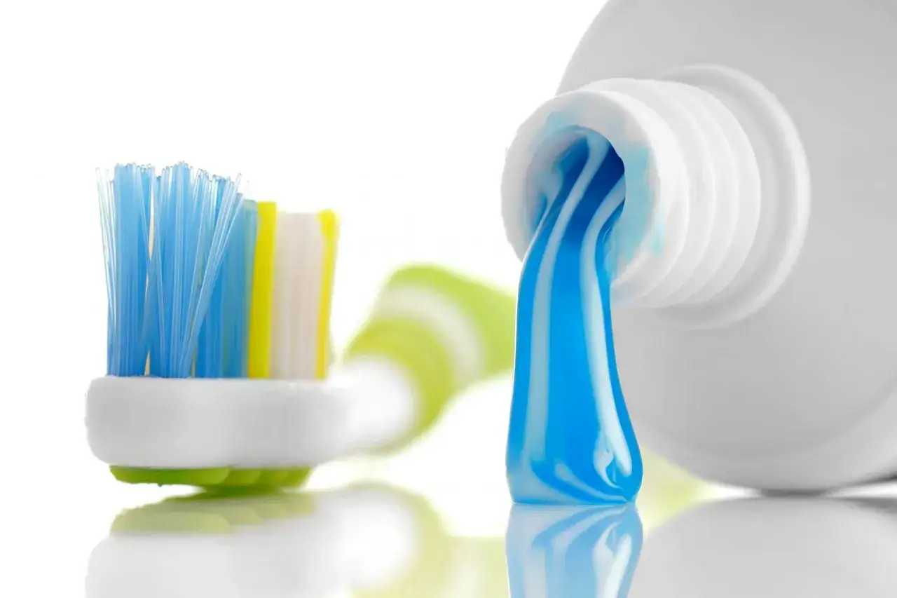 Cepillo de dientes con pasta azul y blanca lista para usar. Un sorbo de agua despu&eacute;s de lavarse los dientes refresca.