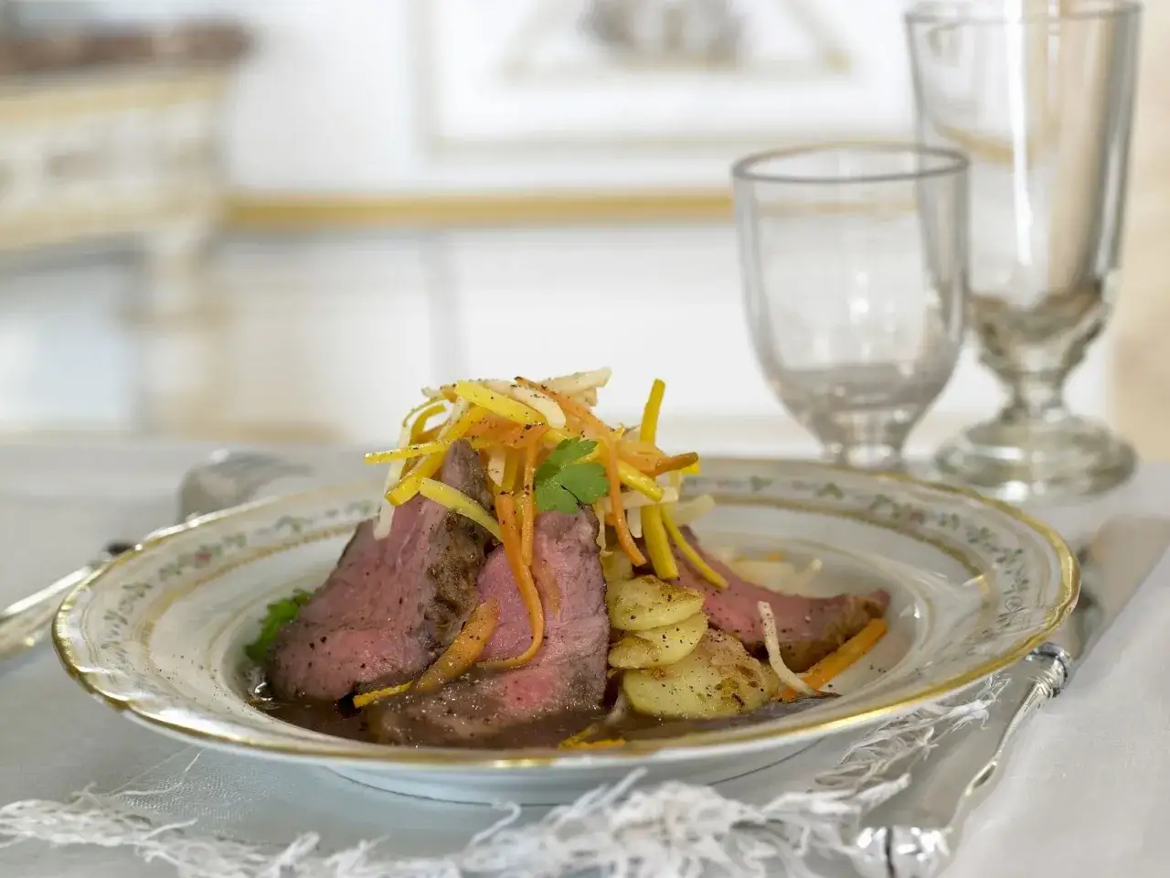 Zartes Roastbeef als Beilage, garniert mit julienniertem Gemüse und Kartoffelscheiben auf einem eleganten Teller.