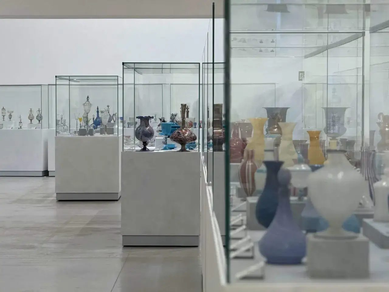 Exposition de vases en verre coloré dans des vitrines, un aperçu du musée du verre Murano.