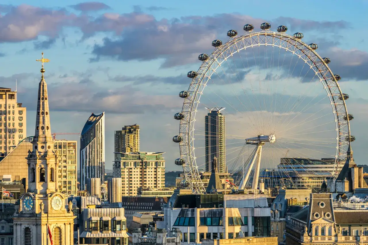 Widok na panoramę Londynu z dominującym London Eye. W tle chmury i nowoczesne budynki.