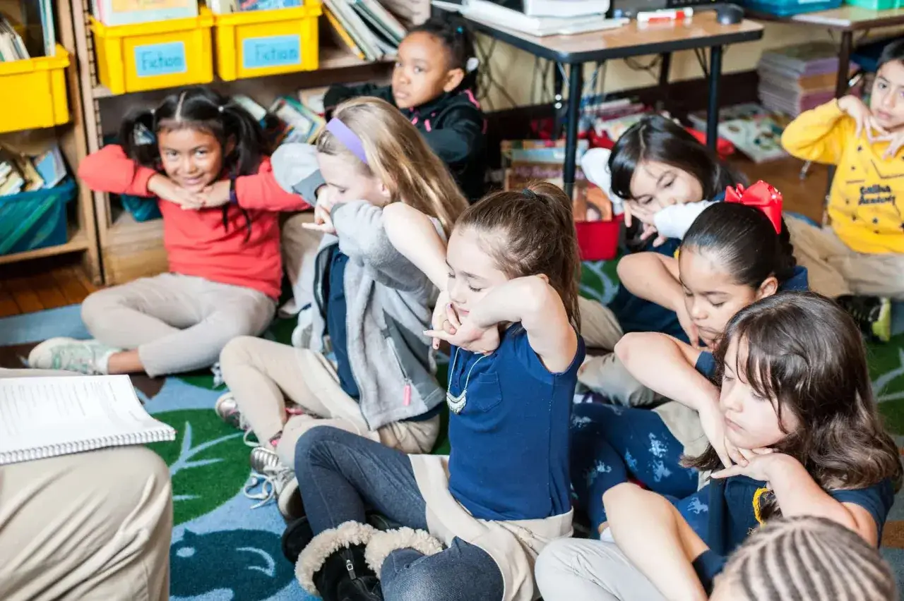 Kinder &uuml;ben im Klassenzimmer Achtsamkeit. Ein achtsamkeit lehrer leitet sie an, sich zu entspannen und auf ihren Atem zu konzentrieren.