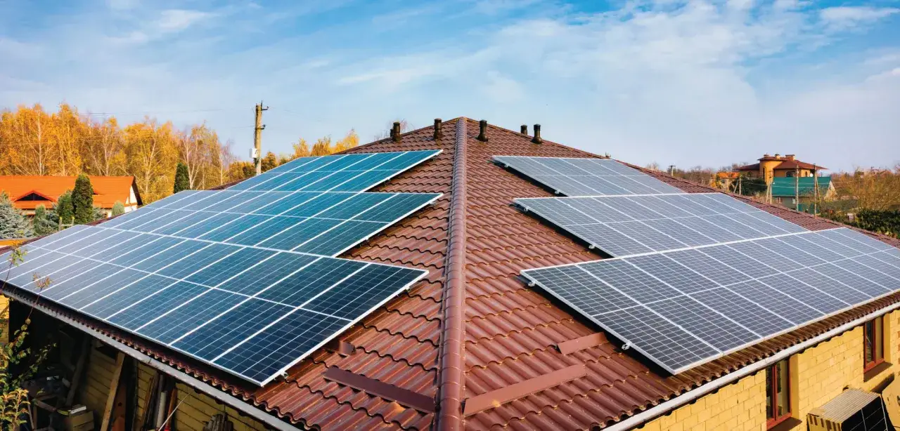 Solceller monterade p&aring; ett tegeltak. Ett hus med solpaneler som f&aring;ngar solens energi.